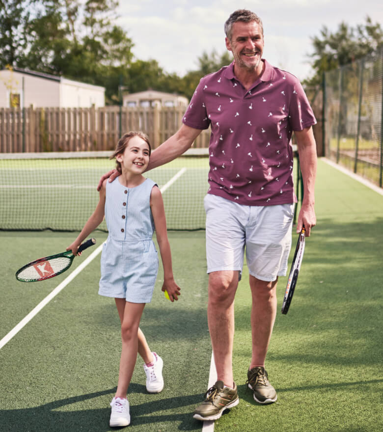 Father playing tennis with daughter.