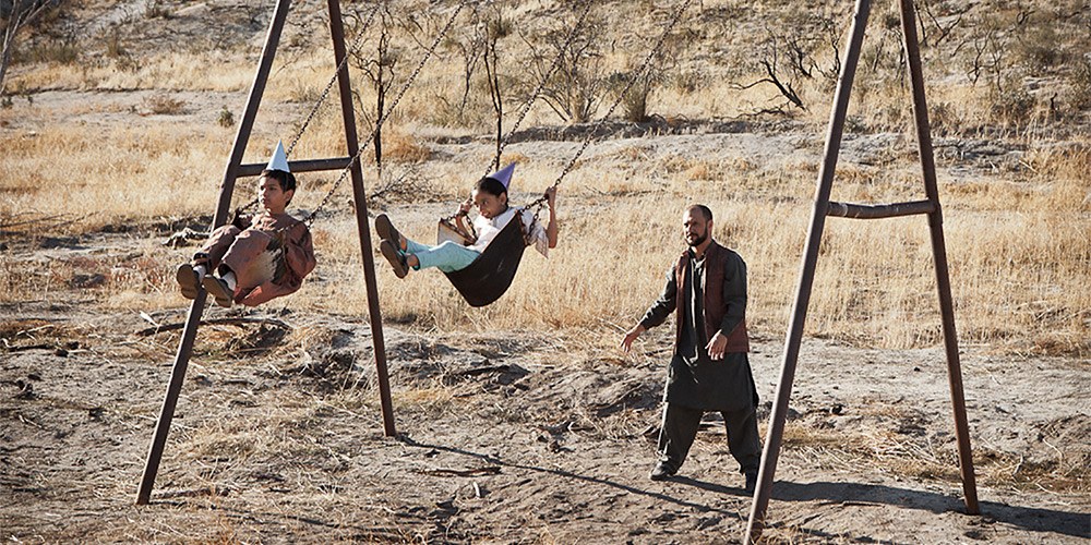 Father pushing children on swings