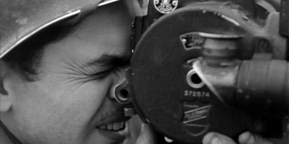 Close-up black and white picture of a soldier holding a film-camera from the 1940s