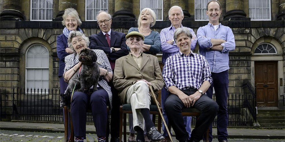 Eight participants of Secret History of our Streets sit in front of their homes