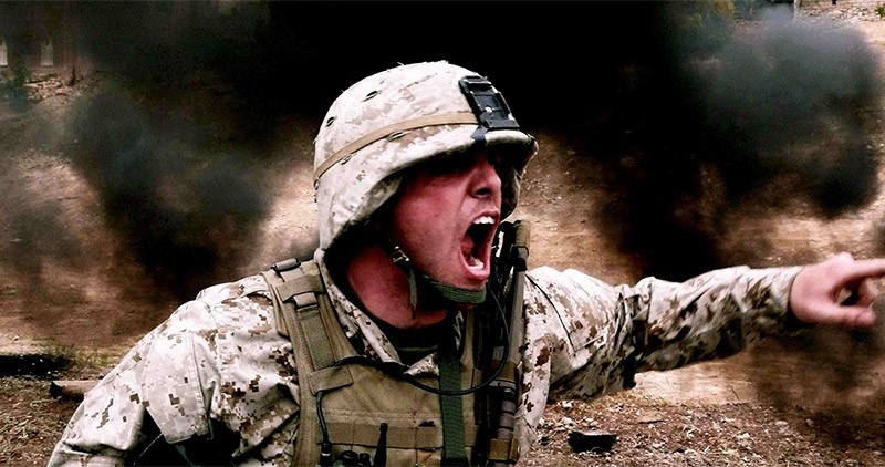 Soldier shouting orders in combat, surrounded by smoke