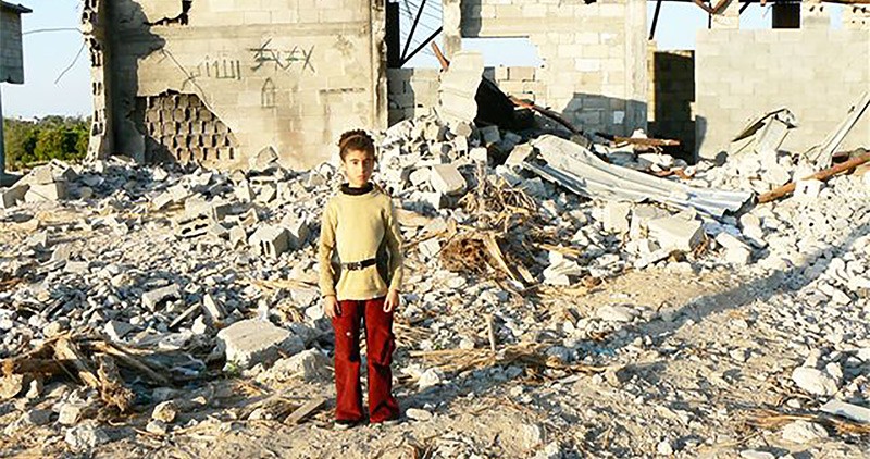 Young child standing among rubble